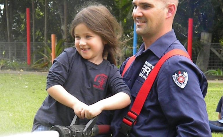 Kindergarten student Ruby Nichol and Fireman Hugh take aim at an orange safety cone. Kindergarten student Ruby Nichol and Fireman Hugh take aim at an orange safety cone.